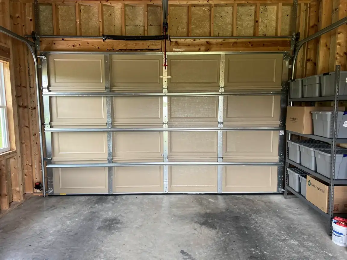 The tan garage door is closed, with a storage shelf to the right.
